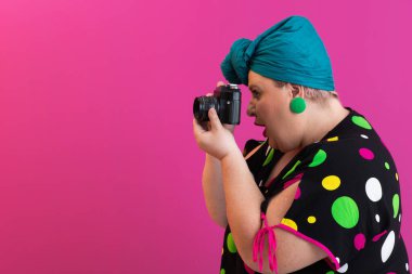 Polka noktalı elbise giymiş kendinden emin bir kadın canlı pembe arka planda kamerayı yan açıdan hedefliyor.. 