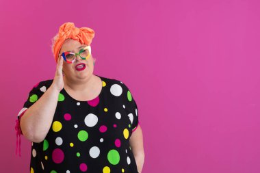 Artı puantiyeli kadın pembe arka planda karışık bir ifadeyle omuz silkiyor.. 