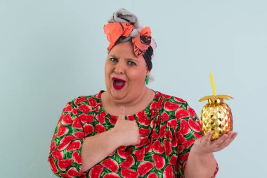 Karpuz desenli elbisesi olan, elleri açık, açık ve açık mavi arkaplan önünde şaşkın, şaşkın bir yüz ifadesi sergileyen neşeli, iri yarı bir kadın.. 