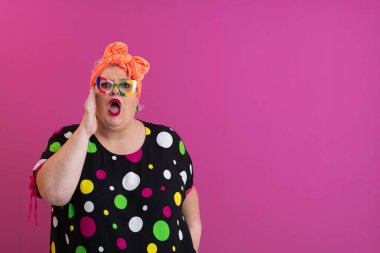 Artı puantiyeli kadın pembe arka planda karışık bir ifadeyle omuz silkiyor.. 