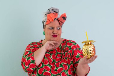 Karpuz desenli elbisesi olan, elleri açık, açık ve açık mavi arkaplan önünde şaşkın, şaşkın bir yüz ifadesi sergileyen neşeli, iri yarı bir kadın.. 