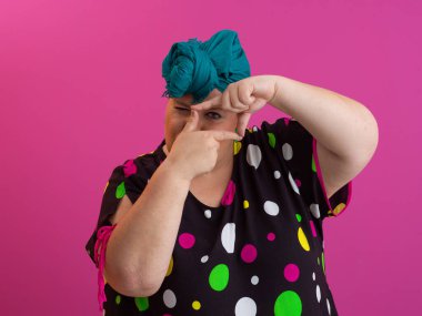 Yaratıcı artı cüsseli kadın parmaklarıyla dikdörtgen yapıyor, pembe arka planda kamera görüntüleyicisi canlandırıyor.. 