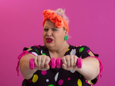 Artı renkli puantiyeli kadın kaşlarını kaldırmış, parlak pembe arka planda şüpheli bir yüz ifadesi takınıyor.. 