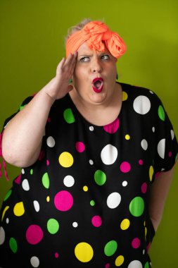 Artı canlı polka noktalı kıyafetli cüsseli kadın uzanmış elleri ve komik ifadesiyle komik omuz silkme hareketi yapıyor. 