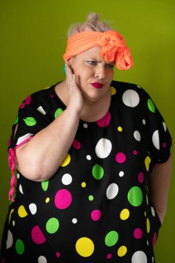 Artı canlı polka noktalı kıyafetli cüsseli kadın uzanmış elleri ve komik ifadesiyle komik omuz silkme hareketi yapıyor. 