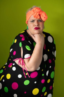 Artı canlı polka noktalı kıyafetli cüsseli kadın uzanmış elleri ve komik ifadesiyle komik omuz silkme hareketi yapıyor. 