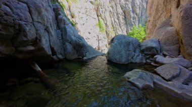 Bereketli yeşil ağaçlar ve ormanlarla çevrili kayalık bir uçurumdan şelalenin havadan görünüşü güneşli bir yaz gününde yumuşak FPV insansız hava aracıyla çekilmiştir, doğa için mükemmeldir.