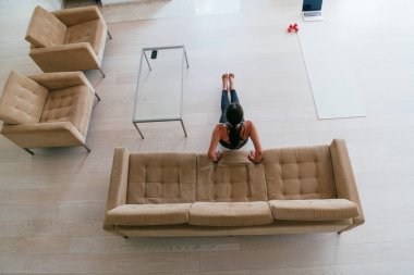 Evde antrenman. Sportif adam antrenman yaparken dizüstü bilgisayarda özel ders izliyor oturma odasında egzersiz yapıyor, boş yer var.