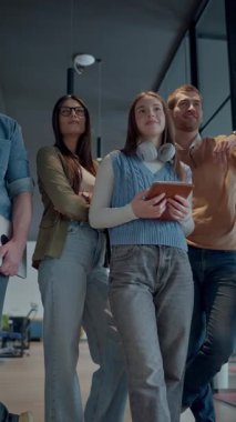 Modern bir ortak çalışma ofisindeki çeşitli profesyonellerden oluşan bir ekip, birlikte gülümsüyor, takım çalışması, işbirliği ve yenilikleri destekleyen pozitif bir şirket kültürü ve dinamik bir çalışma sergiliyor.