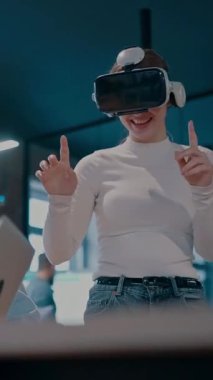 Modern bir iş yerinde çalışan tekerlekli sandalyedeki engelli bir iş kadını. Çevredeki ekip sanal gerçeklik gözlükleri kullanıyor, açık alan yaratıcılığında en son teknolojiyle işbirliği yapıyorlar.