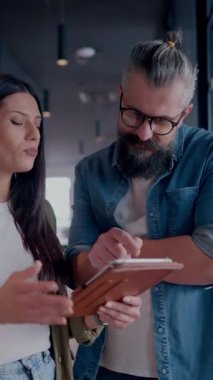 Yaratıcı milenyumlar, sıradan iş adamları, küçük işletme sahipleri, sosyal medya stratejisi ve marka geliştirme üzerinde çalışan modern, açık bir ofis ortamında dijital tabletle