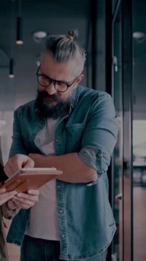 Yaratıcı milenyumlar, sıradan iş adamları, küçük işletme sahipleri, sosyal medya stratejisi ve marka geliştirme üzerinde çalışan modern, açık bir ofis ortamında dijital tabletle