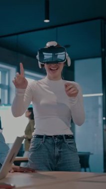 Modern bir iş yerinde çalışan tekerlekli sandalyedeki engelli bir iş kadını. Çevredeki ekip sanal gerçeklik gözlükleri kullanıyor, açık alan yaratıcılığında en son teknolojiyle işbirliği yapıyorlar.