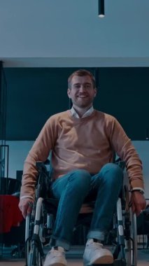 Tekerlekli sandalyede engelli bir işadamının olduğu, cam duvarlı modern bir ofis koridoru. Uzay sergilerinde geniş kapsamlı, erişilebilir bir işyeri, parlak, açık bir tasarımı var.