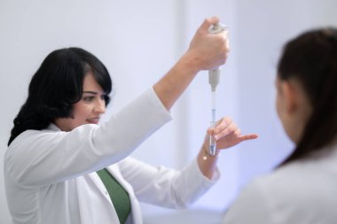 Laboratuvar deneyi sırasında test tüplerindeki sarı kimyasal sıvıyı inceleyen iki kadın bilim adamına yaklaş..