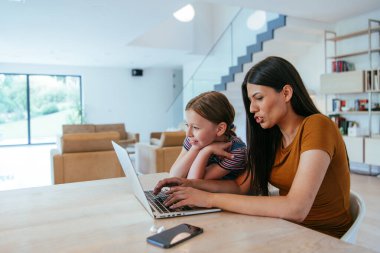 Anne ve kızı dizüstü bilgisayarda ailesi ve arkadaşlarıyla konuşuyorlardı. Büyük evin modern oturma odasında oturuyorlardı.