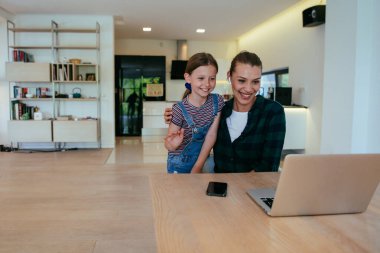 Anne ve kızı dizüstü bilgisayarda ailesi ve arkadaşlarıyla konuşuyorlardı. Büyük evin modern oturma odasında oturuyorlardı.