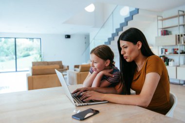 Anne ve kızı dizüstü bilgisayarda ailesi ve arkadaşlarıyla konuşuyorlardı. Büyük evin modern oturma odasında oturuyorlardı.