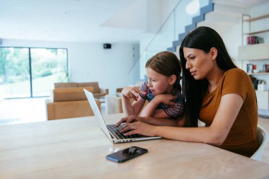 Anne ve kızı dizüstü bilgisayarda ailesi ve arkadaşlarıyla konuşuyorlardı. Büyük evin modern oturma odasında oturuyorlardı.