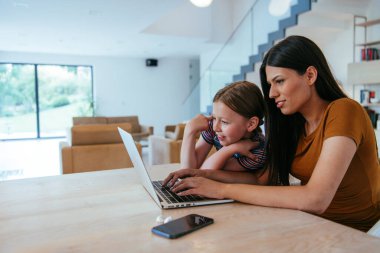 Anne ve kızı dizüstü bilgisayarda ailesi ve arkadaşlarıyla konuşuyorlardı. Büyük evin modern oturma odasında oturuyorlardı.