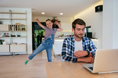 Evden çalışıyorum. Kızı, modern oturma odasında otururken bilgisayarında iş görüşmesi yaparken babasının sözünü kesiyor.