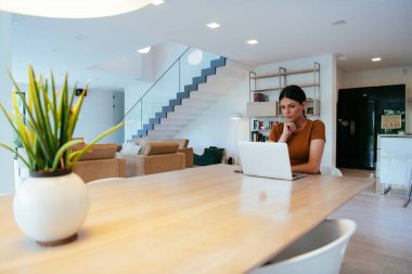 Oturma odasında oturan bir kadın bilgisayarla kameraya bakıyor iş arkadaşlarıyla görüntülü konuşma, vesikalık fotoğraf. İş görüşmesi soruları yanıtlıyor