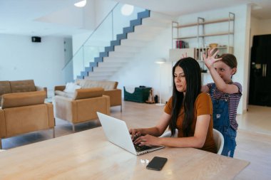 Anne ve kızı dizüstü bilgisayarda ailesi ve arkadaşlarıyla konuşuyorlardı. Büyük evin modern oturma odasında oturuyorlardı.