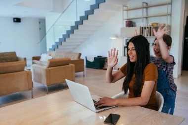 Anne ve kızı dizüstü bilgisayarda ailesi ve arkadaşlarıyla konuşuyorlardı. Büyük evin modern oturma odasında oturuyorlardı.