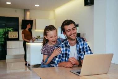 Evden çalışıyorum. Kızı, modern oturma odasında otururken bilgisayarında iş görüşmesi yaparken babasının sözünü kesiyor.