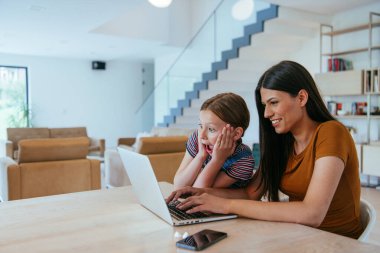 Anne ve kızı dizüstü bilgisayarda ailesi ve arkadaşlarıyla konuşuyorlardı. Büyük evin modern oturma odasında oturuyorlardı.