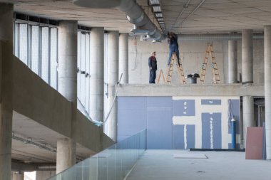 Bir grup işçi, bir bina içine modern bir havalandırma sistemi kurmak, kanalları dikkatlice yerleştirmek ve verimli hava akımını optimal performans için sağlamak için işbirliği yaparlar.. 