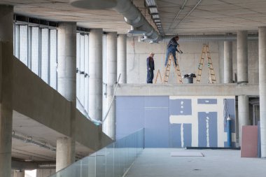 Yapım aşamasındaki modern bir iş binasının büyüleyici bir görüntüsü, çiğ endüstriyel iç mekânını, gün batımının sıcak, altın sarısı renkleri ile yıkanmış çelik kirişleri ve beton duvarlarıyla sergiliyor.. 