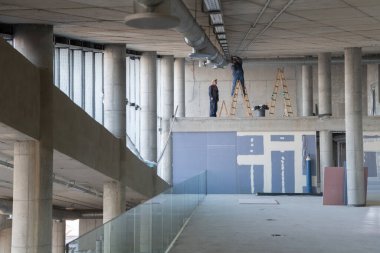 Bir grup işçi, bir bina içine modern bir havalandırma sistemi kurmak, kanalları dikkatlice yerleştirmek ve verimli hava akımını optimal performans için sağlamak için işbirliği yaparlar.. 