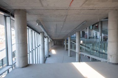 Yapım aşamasındaki modern bir iş binasının büyüleyici bir görüntüsü, çiğ endüstriyel iç mekânını, gün batımının sıcak, altın sarısı renkleri ile yıkanmış çelik kirişleri ve beton duvarlarıyla sergiliyor.. 