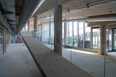 Yapım aşamasındaki modern bir iş binasının büyüleyici bir görüntüsü, çiğ endüstriyel iç mekânını, gün batımının sıcak, altın sarısı renkleri ile yıkanmış çelik kirişleri ve beton duvarlarıyla sergiliyor.. 