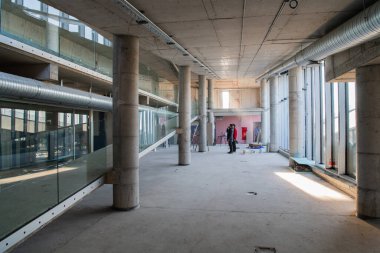 Yapım aşamasındaki modern bir iş binasının büyüleyici bir görüntüsü, çiğ endüstriyel iç mekânını, gün batımının sıcak, altın sarısı renkleri ile yıkanmış çelik kirişleri ve beton duvarlarıyla sergiliyor.. 