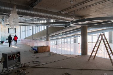 Yapım aşamasındaki modern bir iş binasının büyüleyici bir görüntüsü, çiğ endüstriyel iç mekânını, gün batımının sıcak, altın sarısı renkleri ile yıkanmış çelik kirişleri ve beton duvarlarıyla sergiliyor.. 