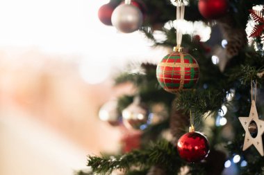 Kırmızı, gümüş ve desenli mücevherleri olan bir Noel ağacını kapatın. Bayram ruhunu ve kış kutlamalarını sembolize eden şenlikli ışıklar ve mevsimlik süslemeler..