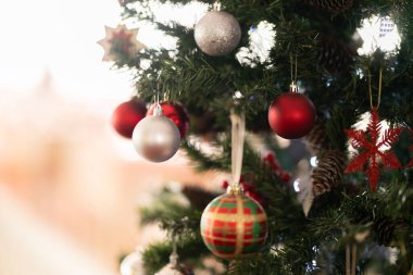 Kırmızı, gümüş ve desenli mücevherleri olan bir Noel ağacını kapatın. Bayram ruhunu ve kış kutlamalarını sembolize eden şenlikli ışıklar ve mevsimlik süslemeler..