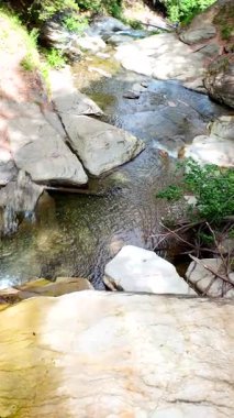 Yeşil ormandaki kayaların üzerinden akan güzel bir şelalenin havadan çekilmiş videosu, temiz su akıntısı olan doğa manzarası, rahatlama ve macera için seyahat yeri. Sinematik ağır çekim dikey