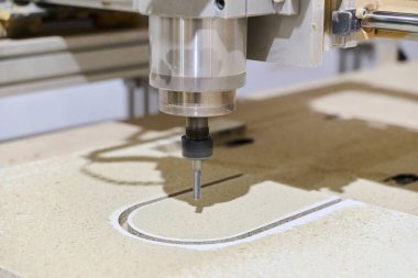 Yüksek hassasiyetle ahşap tahtaları kesen ve işleyen bir CNC makinesinin yakın çekim görüntüsü.