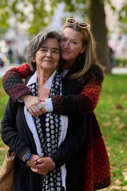 Büyüleyici bir sonbahar gününde, bir kız çocuğu yaşlı annesini sevgiyle kucaklıyor, el ele tutuşuyor ve birlikte huzurlu bir anın tadını çıkarırken sarsılmaz bir destek sunuyor..