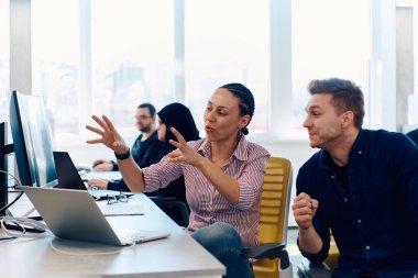 Ofiste yapılan beyin fırtınası sırasında çok kültürlü genç iş adamlarının ortak çalışma süreci. Resmi olarak giyinmiş çeşitli gençler tasarım projesinin geliştirilmesinde işbirliği yapıyor.
