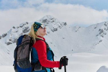 Kararlı bir kayakçı Alplerde karlı bir zirveye tırmanır, destansı bir iniş için taşıma gereçleri taşır.