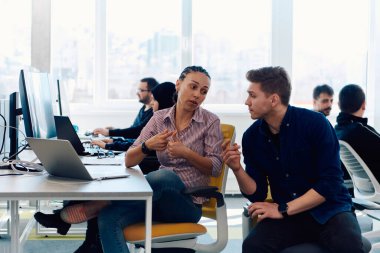 Ofiste yapılan beyin fırtınası sırasında çok kültürlü genç iş adamlarının ortak çalışma süreci. Resmi olarak giyinmiş çeşitli gençler tasarım projesinin geliştirilmesinde işbirliği yapıyor.