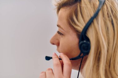 Dost canlısı çağrı merkezi ajanı gelen aramalara kulaklıkla cevap veriyor, müşteri hizmetlerini uzaktan sağlıyor. Müşteri sorunlarını çözmek için mükemmel iletişim yeteneklerini kullanan mutlu bir kadın.. 