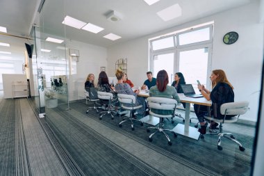 Çeşitli iş adamları modern cam duvarlı bir ofisteki projeler hakkında tartışmaya giriştiler.. 