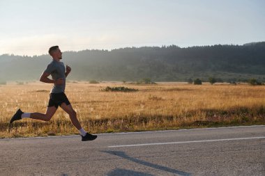 Atletik bir adam koşarken kararlılığını sergiler, sağlıklı bir yaşam tarzına ve yaklaşan maraton yarışmasına hazırlanmaya bağlıdır.