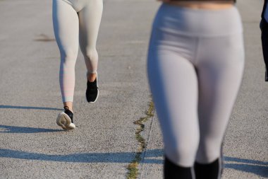 Bir atletik koşucunun kaslı bacakları hareketli, parlak bir günde güneş ışığıyla aydınlatılır..