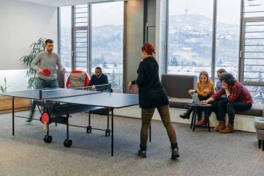  İş arkadaşları masa tenisi oynamak, iş yerinde takım çalışması ve arkadaşlığı teşvik etmek için işe ara veriyorlar.. 